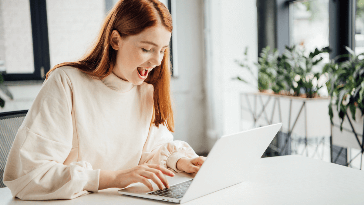 Smiling girl sitting at table and using laptop at home