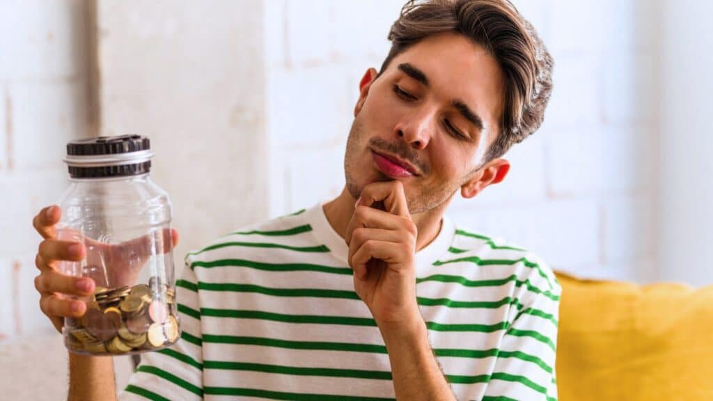 Man holding a jar with coins inside